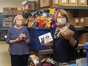 Women stand in a warehouse with a bin of prepackaged pet food