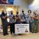 a group of men and women in scrubs stand holding cats, while wearing face masks. A man kneels in front holding a sign with a cat and dog on it saying "happy 70th birthday Blue Ridge Humane Society"