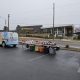 image of a brightly decorated van with tables set up behind it with piles of bagged pet food. In the background in a modern looking one story building with "boys and girls club of Henderson County" written on it.