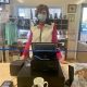 a woman wearing a mask stands behind a cash register