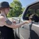 a side view of a woman feeding a treat to a dark colored dog sitting inside a truck