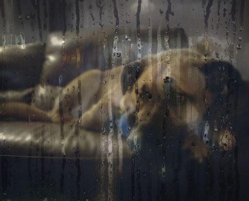 Looking through a wet window on a dog laying on a couch