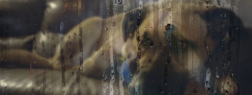 Looking through a wet window on a dog laying on a couch