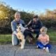 a women, man, and young child pose with a multicolored medium sized dog