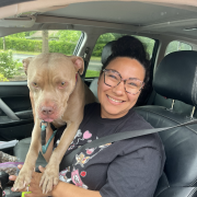 A woman in a car with a large tan dog