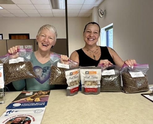 Two people pose with treats, litter, and pet