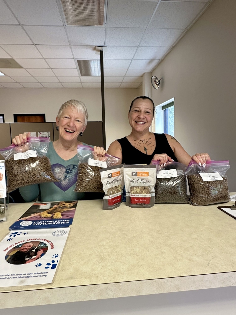 Two people pose with treats, litter, and pet