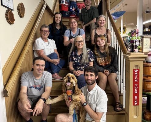 Several people pose with a dog on stairs