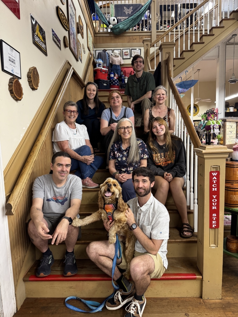 Several people pose with a dog on stairs