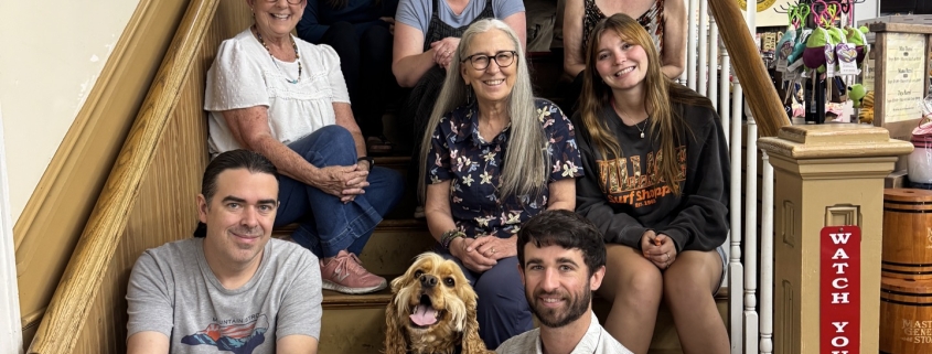 Several people pose with a dog on stairs