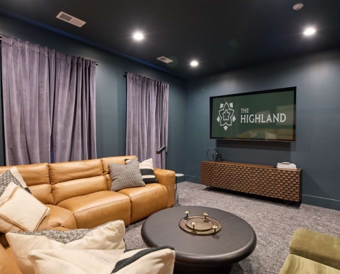 A couch in a room with a TV that says "The Highland"